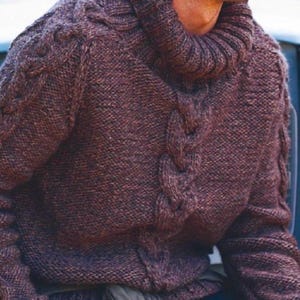 May include: A brown cable-knit sweater with a high, rolled collar. The sweater features a textured, braided design down the front and on the sleeves. The warm, cozy knitwear is perfect for cold weather.