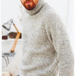 May include: A light gray, textured knit turtleneck sweater. The sweater has a high collar and long sleeves. The person is wearing blue jeans. The sweater appears to be made of a thick, warm material, suitable for cooler weather.