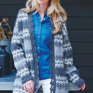 May include: A long, open-front cardigan in shades of gray and white with a geometric pattern. The sweater has a scalloped edge and is worn over a blue denim shirt and white pants. The model has long blonde hair.