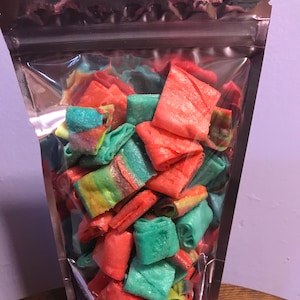 May include: A clear plastic bag filled with colorful, rolled candy. The candy is a mix of red, green, and rainbow colors.
