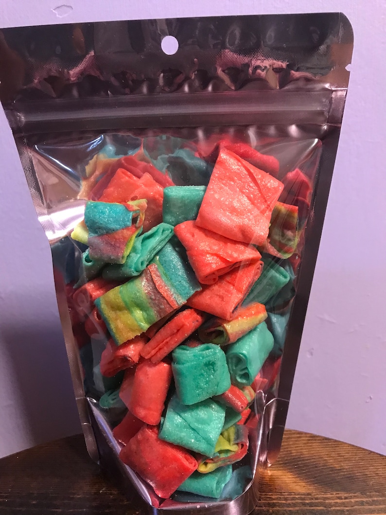 May include: A clear plastic bag filled with colorful, rolled candy. The candy is a mix of red, green, and rainbow colors.