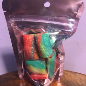 May include: A clear plastic bag filled with colorful, swirl-shaped candies. The candies are red, green, and yellow.