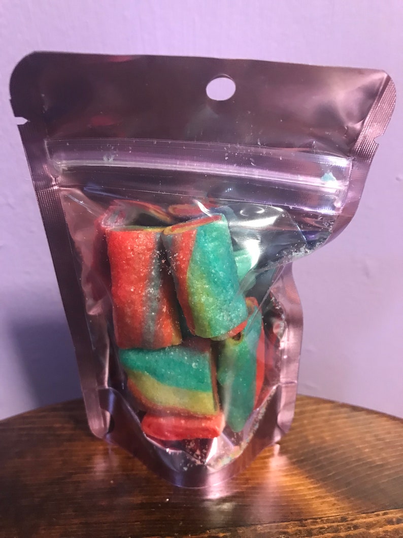 May include: A clear plastic bag filled with colorful, swirl-shaped candies. The candies are red, green, and yellow.