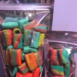 May include: Two clear plastic bags filled with colorful rainbow swirl candy. The candy is in the shape of small rolls. The larger bag is filled with more candy than the smaller bag.
