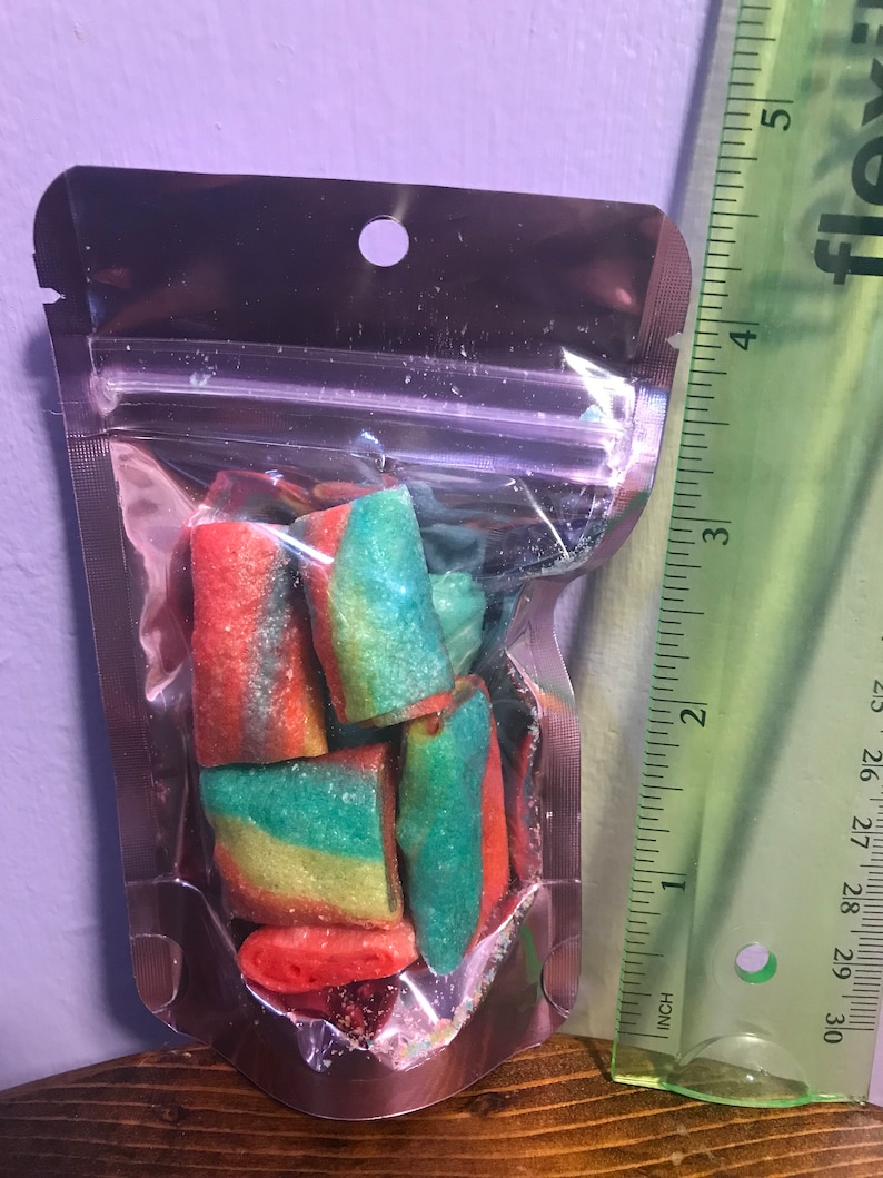 May include: A small clear plastic bag with a silver zipper closure contains a variety of colorful candy. The candy is in the shape of small, twisted tubes and is red, green, and yellow.