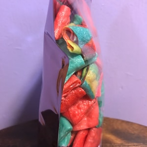 May include: A clear plastic bag filled with colorful, crunchy, bite-sized snacks. The snacks are a mix of red, green, and yellow.