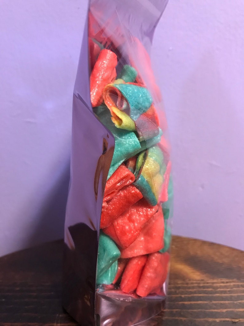 May include: A clear plastic bag filled with colorful, crunchy, bite-sized snacks. The snacks are a mix of red, green, and yellow.