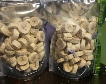 May include: Two clear plastic bags filled with dried banana slices. The bags are sealed and have a zipper closure. A ruler is visible in the background.