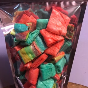 May include: A clear plastic bag filled with colorful, rolled candy. The candy is a mix of red, green, and yellow.