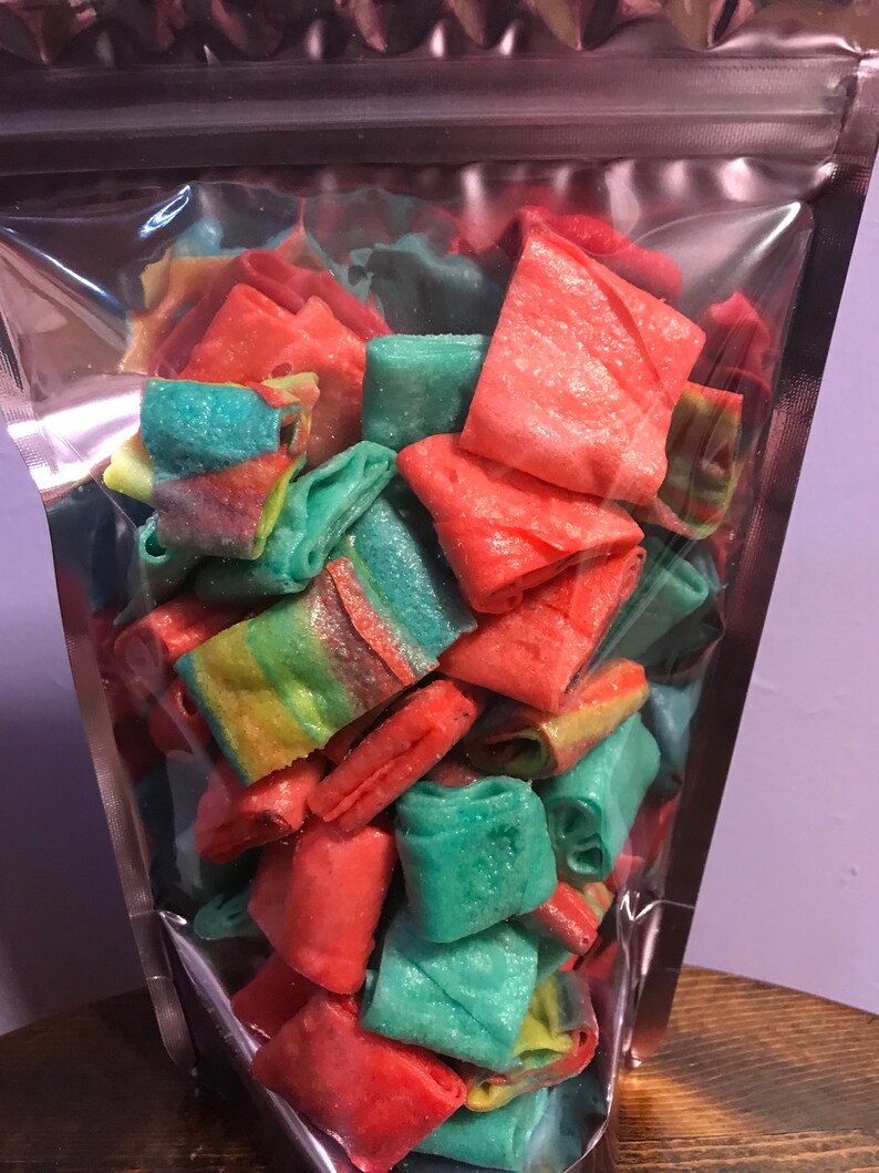 May include: A clear plastic bag filled with colorful, rolled candy. The candy is a mix of red, green, and yellow.