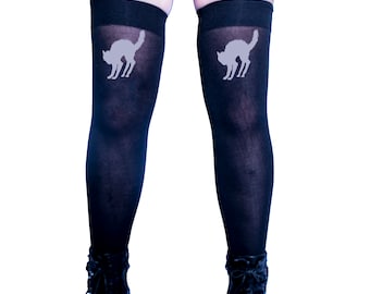 May include: Black thigh-high stockings with a white cat silhouette design on each leg. The stockings are worn with black heeled boots.