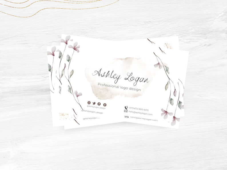 Op de afbeelding: Een witte visitekaartje met een aquarel bloemenontwerp en de tekst "Ashley Logan, Professioneel logo ontwerp". De kaart bevat ook contactgegevens, waaronder een telefoonnummer, e-mailadres en links naar sociale media.