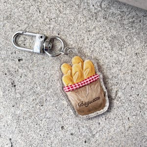 Paris Illustration Schlüsselanhänger: Baguette Anhänger, AirPods Accessoire aus Acryl