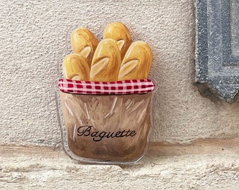 Puede incluir: Una bolsa de plástico transparente con un patrón de cuadros rojos y blancos contiene un montón de baguettes doradas. La bolsa está etiquetada con "Baguette".