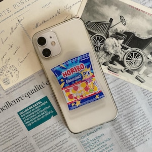 Peut inclure: Un étui de téléphone transparent avec un autocollant d'un sac de bonbons Horibo Orangino Pik. Le sac est bleu avec le nom de la marque et des bonbons.