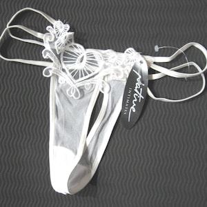 May include: White lace lingerie with a delicate floral design and a tag that reads "Intime Intimates".