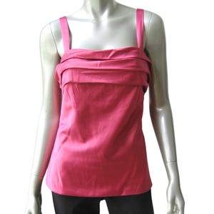 以下が含まれることがあります： スクエアネックラインとバストにドレープディテールが施された、ピンクのサテンのノースリーブトップです。