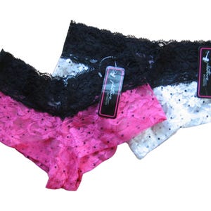 May include: Three pairs of lace underwear in pink, white, and black. The underwear features a lace trim and a dotted pattern. Each pair has a tag attached. The underwear is designed for comfort and style.