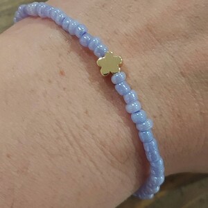 May include: A light blue beaded bracelet with a gold flower charm.