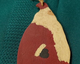 May include: Wooden Santa Claus Christmas ornament. The ornament is painted with a red coat, a cream-colored beard and hat trim, and black boots. A jute twine loop is attached for hanging. The ornament has a rustic, handmade appearance.