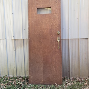 May include: A solid wood door with a single rectangular window pane. The door has a brass door handle and a brass door knob. The door is brown and has a wood grain pattern.