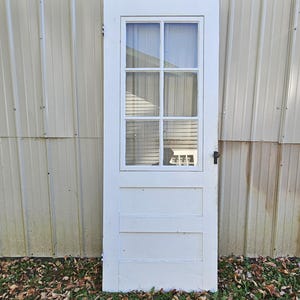 May include: White wooden door with a six-pane glass window and a simple white trim. The door has three horizontal panels below the window.
