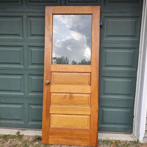May include: A wooden door with a rectangular glass window at the top. The door has a light brown finish and four horizontal panels below the window. A brass doorknob is visible on the left side. The date "September 18, 2025" is written in the bottom right corner.