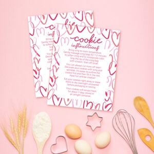 May include: Pink and white printable instructions for decorating cookies with hearts and the text "Cookie Instructions". The instructions include tips for decorating cookies with icing and sprinkles.