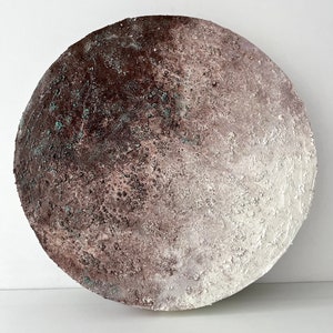 May include: A round, white and brown ceramic wall art piece with a textured surface. The piece has a gradient of color from dark brown to white.