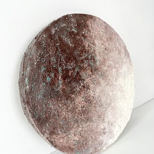 May include: A round, brown and white ceramic plate with a textured surface. The plate has a gradient of color, with the brown color fading to white.