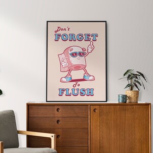 May include: A humorous poster with a cartoon toilet paper roll wearing sunglasses and saying "Don't forget to flush". The poster has a pink background with blue and red text.