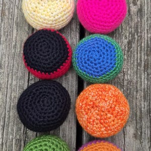 May include: Eight colorful, handmade crochet circles in various colors, including yellow, pink, navy blue, blue, orange, and green. The circles are arranged in two rows of four on a weathered wooden surface. Each circle has a unique color combination.