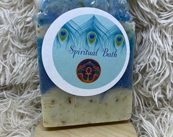 May include: A blue and white bar of soap with a white circle label that says "Spiritual Bath". The label has a peacock feather design and a symbol in the center.