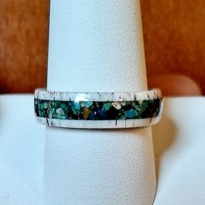 May include: A white ring with a band of turquoise, green, and gold inlay.