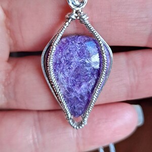 May include: A purple and silver wire-wrapped pendant featuring a natural amethyst stone. The pendant is on a silver chain.
