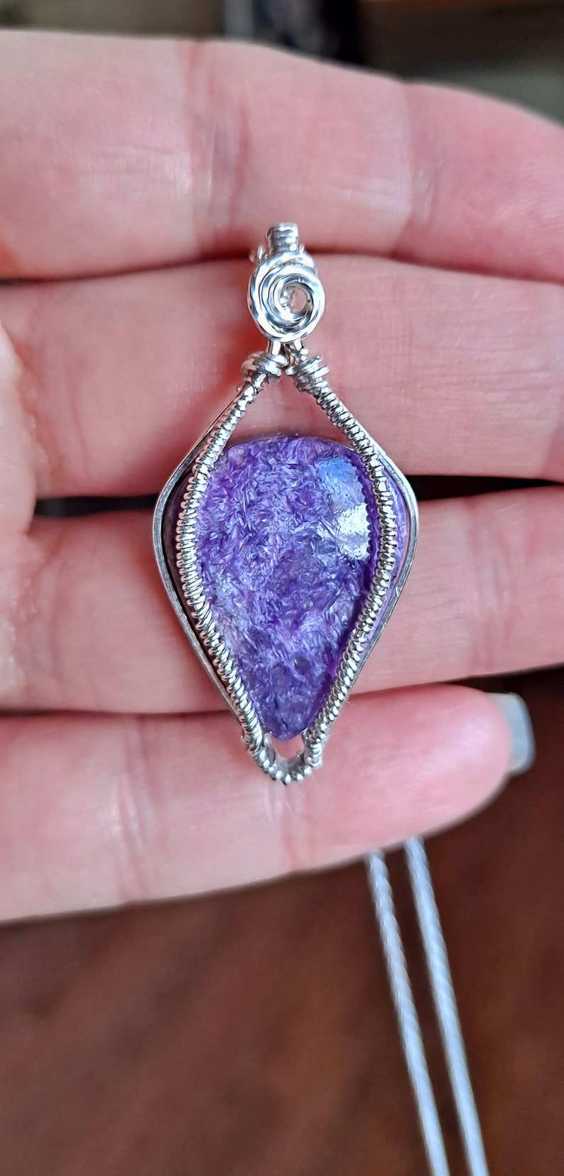 May include: A purple and silver wire-wrapped pendant featuring a natural amethyst stone. The pendant is on a silver chain.