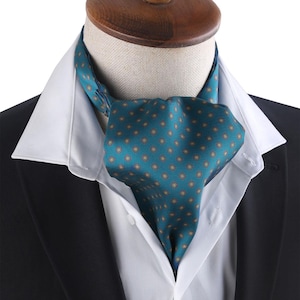 Könnte beinhalten: Eine blaugrüne Krawatte mit einem kleinen, sich wiederholenden Muster aus gelben und roten Quadraten. Die Krawatte ist um einen weißen Hemdkragen und einen schwarzen Anzugsakko gebunden.