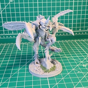 May include: A gray plastic miniature of a creature with wings, claws, and a horn. The creature is standing on a round base with a textured surface.