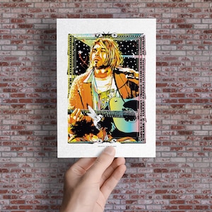 May include: A pop art style print featuring a musician playing a guitar. The image has a colorful design with orange, yellow, blue, and black tones. The print is held against a brick wall.