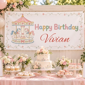 Può includere: Uno striscione di compleanno rettangolare bianco con un'illustrazione di una giostra, il testo Happy Birthday Vivian e bordi floreali. Lo striscione è esposto sopra un tavolo con una torta a due piani, cupcake, ciambelle, macaron e due insegne.