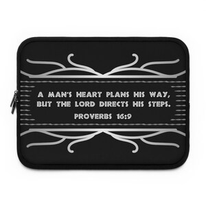 May include: Black laptop sleeve with a silver design featuring the quote "A man's heart plans his way, but the Lord directs his steps." and the scripture reference "Proverbs 16:9".
