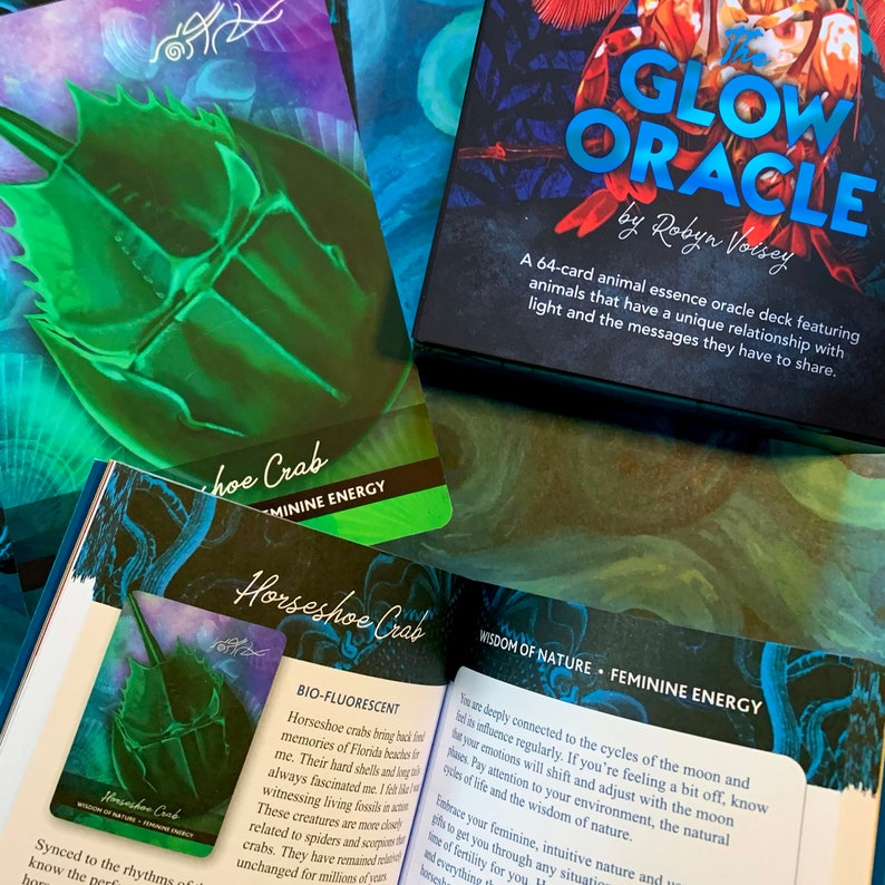 Peut inclure: Gros plan sur une carte du jeu d'oracle Glow Oracle, repr&eacute;sentant un crabe fer &agrave; cheval avec une lueur biofluorescente. Le titre de la carte est "Horseshoe Crab" et le texte indique "Wisdom of Nature - Feminine Energy".