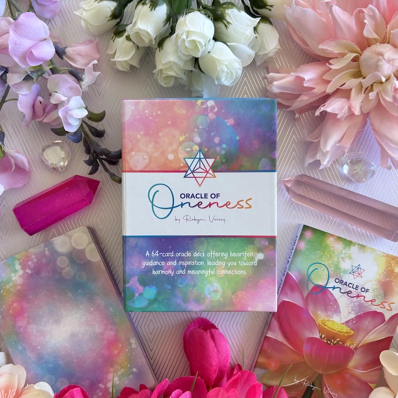May include: A box of Oracle of Oneness cards by Robyn Vocery. The box has a colorful design with a rainbow background and a star in the center. The text on the box reads "Oracle of Oneness by Robyn Vocery". The box is surrounded by pink flowers and crystals.