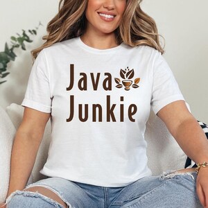 May include: A white t-shirt with the text "Java Junkie" in brown lettering. A coffee cup with leaves is above the word "Junkie".