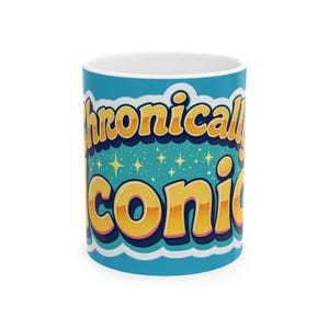 May include: A white ceramic mug with a vibrant design. The mug features the words "Chronically Iconic" in a retro font with yellow and orange lettering, outlined in blue. The background is a teal color with white stars.