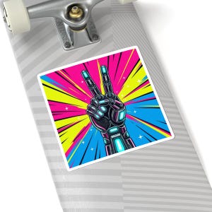 May include: A sticker featuring a robotic hand making the peace sign. The hand is black with blue and teal accents, set against a vibrant background of pink, yellow, and blue rays. The sticker is rectangular with rounded corners.