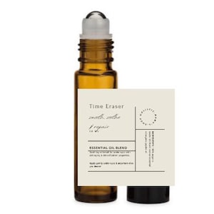 May include: A brown glass roller bottle with a clear glass roller ball and a white label. The label says "Time Eraser" and "smooth, soothe & repair 10 ml". The label also says "Essential Oil Blend" and lists ingredients.