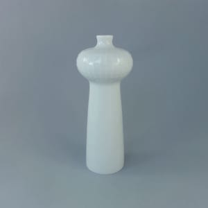 Puede incluir: Un jarrón de cerámica blanco con una parte superior bulbosa texturizada y una base alta y delgada.