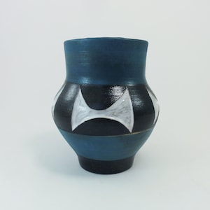 May include: A small, blue ceramic vase with black and white geometric designs. The vase has a rounded body and a narrow opening.