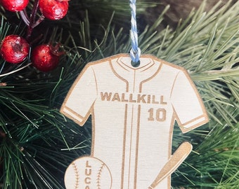 以下が含まれることがあります： 野球をテーマにした木製クリスマスオーナメント。「WALLKILL」の文字と「10」の数字がプリントされた野球のユニフォームの形をしています。野球ボールとバットも含まれています。「LUCAS」という名前が野球ボールにプリントされています。